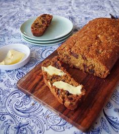 a loaf of bread sitting on top of a wooden cutting board next to a bowl of butter