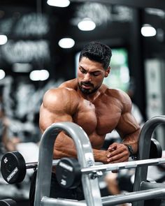 a man is working out with his hands on the barbells in a gym