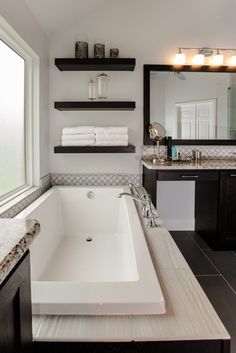 a large white bath tub sitting next to a bathroom sink under a mirror in a bathroom