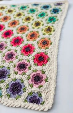 a crocheted blanket with multicolored flowers on it