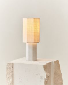 a lamp that is sitting on top of a block of concrete with a white background