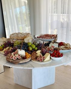 a table topped with lots of different types of cheeses and fruit on top of it