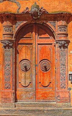 an old wooden door with ornate carvings on the front and side doors are painted orange