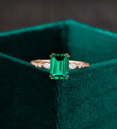 an emerald and diamond ring in a green velvet box