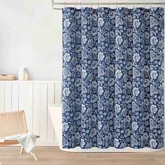 a shower curtain with blue and white flowers on it in a bathroom next to a bathtub