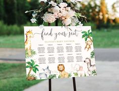 a baby shower sign with animals and flowers on it in front of a park setting