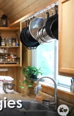 a kitchen with pots and pans hanging from the ceiling, next to a window