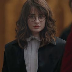 a woman with glasses standing in front of a man wearing a suit and bow tie