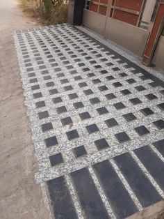 an outdoor walkway made out of black and white tiles on the side of a building