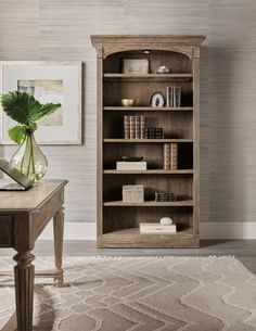 a wooden bookcase sitting on top of a carpeted floor next to a table