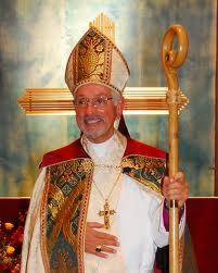 a man in a priest's outfit holding a large golden pole with a cross on it