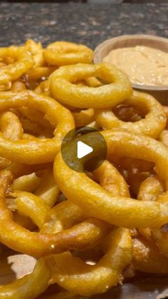 a pile of onion rings sitting on top of a table next to a bowl of mustard