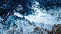 an aerial view of the ocean with waves crashing on the rocks and water splashing over them