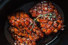 two chicken wings covered in bbq sauce and garnished with sprigs