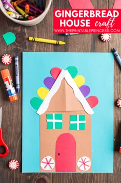 a gingerbread house craft made out of construction paper and colored crayons on a wooden table