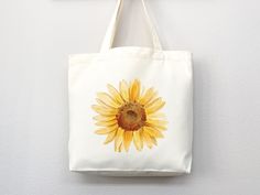 "Carry the sunshine with you wherever you go with our Sunflower Tote Bag. Made from durable and eco-friendly materials, this bag features a beautiful sunflower design that is sure to brighten up any outfit. Perfect for everyday use, it has plenty of room for all your essentials and is comfortable to carry with its sturdy handles. Order now and bring a little bit of nature wherever you go! canvas tote bag, flower tote bag, tote bag canvas, eco friendly bag, aesthetic tote, reusable bag, cottageco Yellow Canvas Bag As Gift, Yellow Sunflower Design Bags For Daily Use, Summer Flower-shaped Canvas Bag, Floral Canvas Bag For Daily Use In Summer, White Flower-shaped Canvas Bag For Summer, White Eco-friendly Flower-shaped Canvas Bag, Eco-friendly White Flower-shaped Canvas Bag, Yellow Eco-friendly Canvas Bag As Gift, Yellow Eco-friendly Canvas Bag For Summer