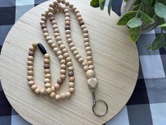 a wooden beaded necklace on a table with a keychain and potted plant in the background