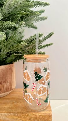 a glass jar with gingerbreads and christmas decorations on it next to a potted tree