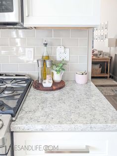 a white kitchen counter top next to a stove and oven with an empty bottle on it