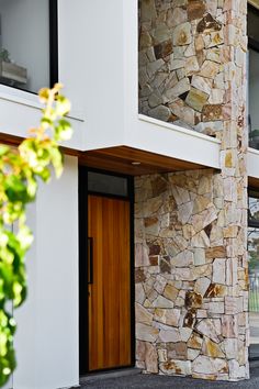 the front entrance to a modern home with stone and wood accents on the outside wall