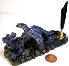 a dragon figurine with a pen in it's mouth next to a penny