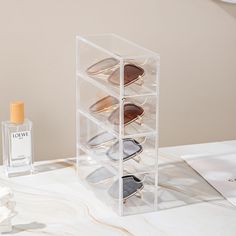 an acrylic display case holds six pairs of sunglasses and a bottle of cologne