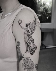 a woman with a tattoo on her arm holding an angel above her head and flowers in the background