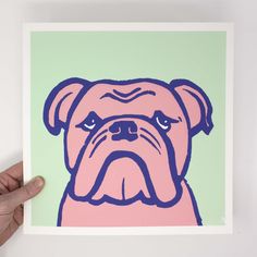 a hand is holding up a pink and blue print with a dog's face