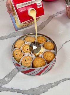 a person pouring sauce on some cookies in a tin