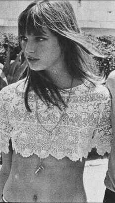 black and white photograph of a woman in short shorts with her shirt open, looking off to the side