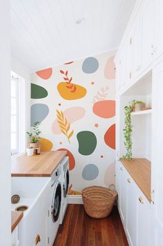 a washer and dryer in a small room with colorful wallpaper on the walls