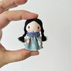 a hand holding a small doll in it's left hand