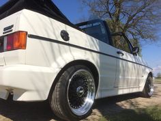 the back end of a white car parked in a field