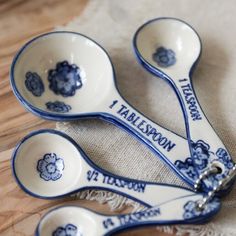 three blue and white measuring spoons sitting on top of a cloth covered tablecloth