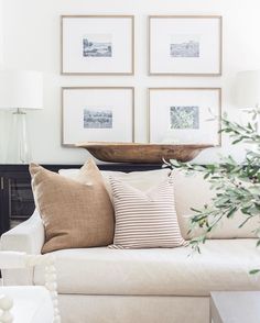 a living room with white couches and pictures on the wall above them, along with a coffee table