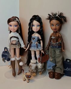 three dolls standing next to each other in front of a wall with purses on it