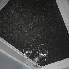 a chandelier hanging from the ceiling in front of a black wallpapered ceiling