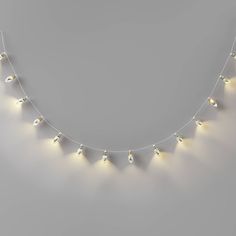 a white necklace with yellow lights hanging from it's sides on a gray background