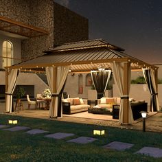 an outdoor living area with couches, tables and lights on the patio at night