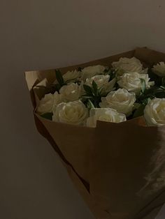 a bouquet of white roses in a brown paper bag