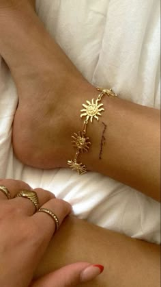 a woman laying in bed with two gold bracelets on her feet