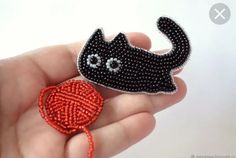 a hand holding a beaded black cat brooch