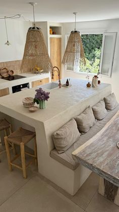 a large kitchen with an island bench in the center and two hanging lights above it