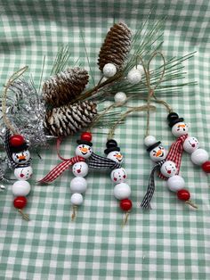 snowmen and pine cones sitting on top of a green checkered tablecloth with christmas decorations