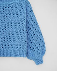 a blue knitted sweater laying on top of a white surface