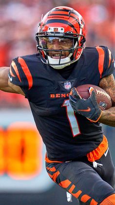 a football player running with the ball in his hand and wearing an orange and black uniform