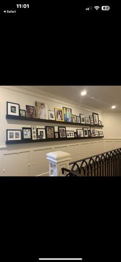 there are many pictures on the wall above the stairs in this house, and one is framed with family photos