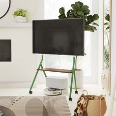 a flat screen tv sitting on top of a stand in a living room next to a potted plant