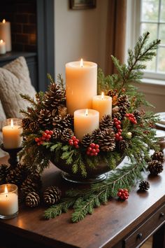 some candles are sitting on a table with pine cones and evergreen branches in the center