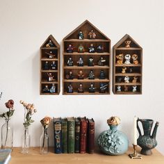 three wooden shelves filled with figurines on top of a table next to vases